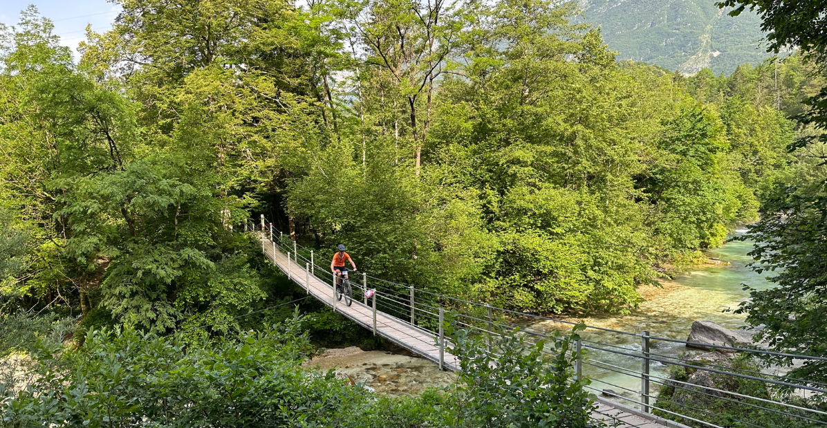 Mountainbiker die over een brug met water eronder fietst