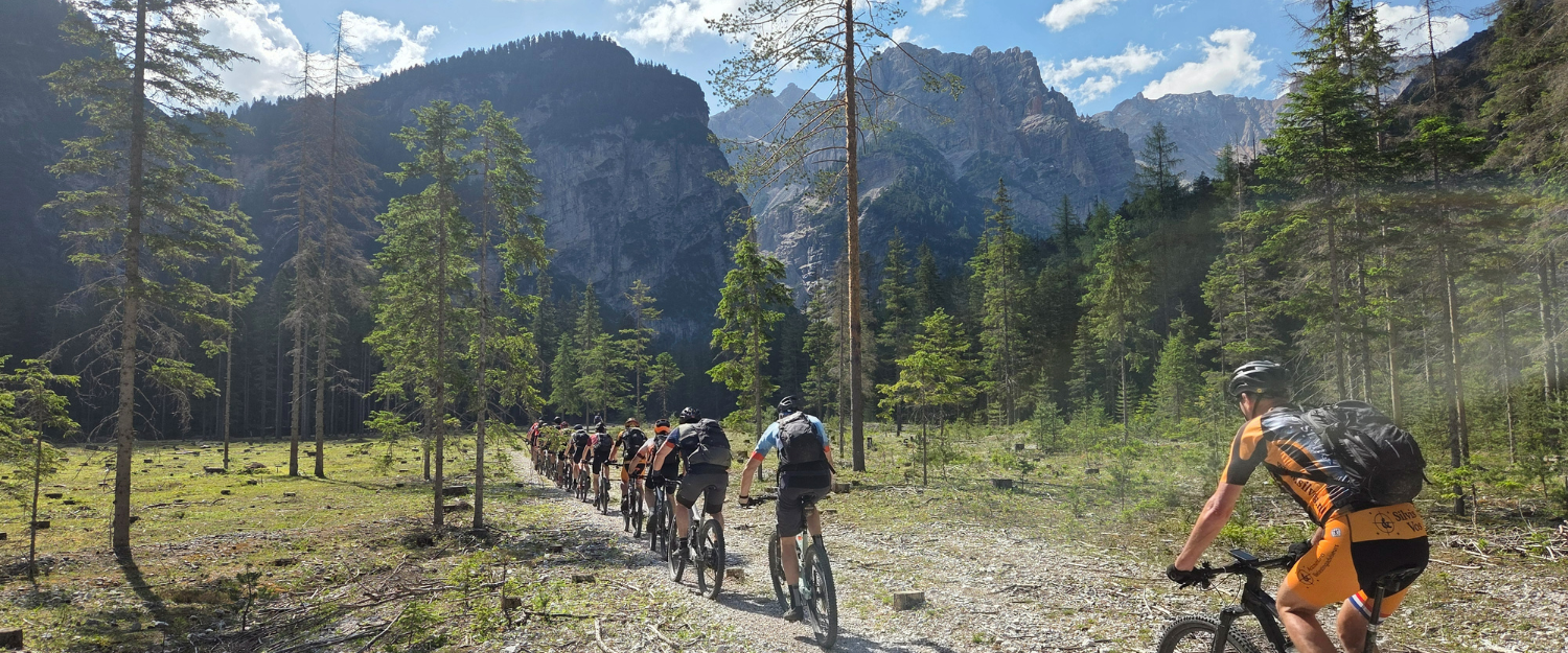 Een grote groep mountainbikers die de dolomieten in fietst