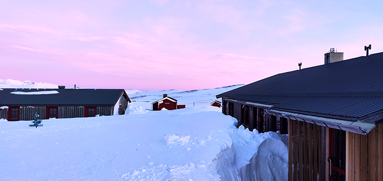 Ingesneeuwde hut onder een roze zonsondergang