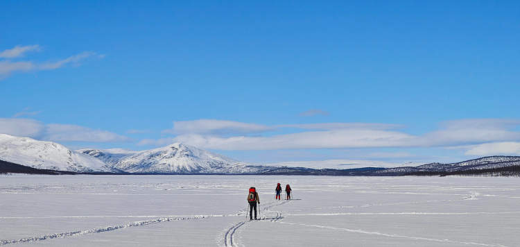 Drie langlaufers die over een bevroren meer skien